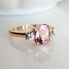 a pink diamond ring sitting on top of a table