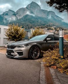 a silver car parked on the side of a road next to a building and mountains