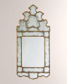 a mirror hanging on the wall with a white and gold border around it's edge