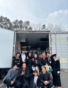 a group of people standing in front of a truck with their hands up to the camera