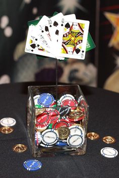 playing cards and chips in a glass container on a table