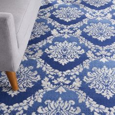 a blue and white area rug with an ornate design on the bottom, in front of a gray couch