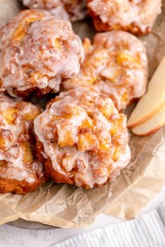 apples and cinnamon donuts with icing on a piece of wax paper next to an apple