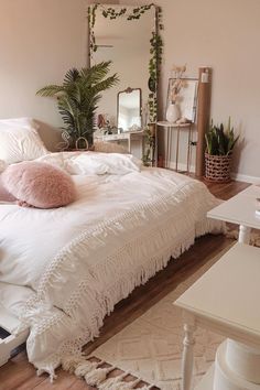 a white bed sitting in a bedroom on top of a hard wood floor next to a mirror