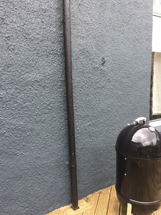 a large black trash can sitting on top of a wooden floor next to a blue wall