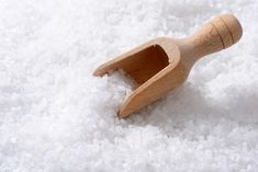 a wooden spoon sitting on top of white sugar