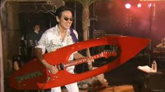 a man holding a red guitar shaped like a rocket ship