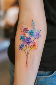 a woman's arm with watercolor flowers on the left side of her arm