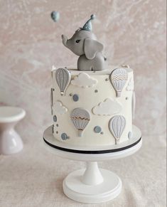 a cake with an elephant on top and hot air balloons in the sky above it