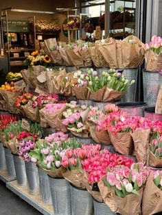 several buckets filled with flowers on display in front of a store