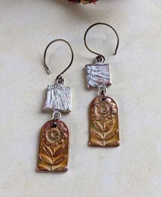 Pair of handmade copper clay earrings stained/altered with golden yellow, creamy white, translucent rose, and other colors. I made these from copper clay that I textured and fired in my studio. I painted the components to create a warm, earthy hue. I used a variety of metal stains which are then sealed with both Renaissance wax and a non-VOC urethane seal. While they're water resistant, it's best not to wear swimming, in the shower, etc. in order to maintain the patina. The ear wires are a warm brown color. I made them from 20g titanium wire and created the color through electrolysis. The jump rings are also made of titanium wire. Each earring weighs 5g. 2.25" long Photos are taking in natural light and are unaltered. OOAK jewelry with a modern folk art vibe. Copper Clay Jewelry, Long Photos, Copper Clay, Art Vibe, Pmc Jewelry, Modern Folk Art, Modern Folk, Art Earrings, Ceramic Earring