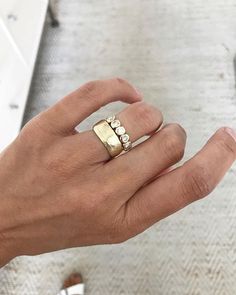 a person's hand with a gold ring on their left and two diamonds on the right