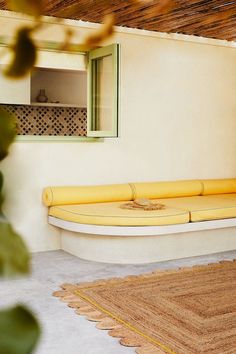 a yellow couch sitting on top of a white floor next to a wooden door and window