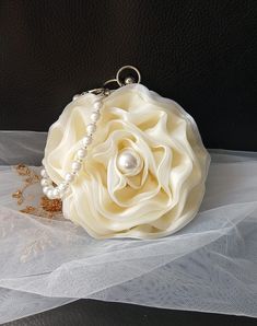 Elevate your special occasion look with this elegant Ivory Organza Flower Evening Clutch Bag. Perfect for brides or bridesmaids, this exquisite handbag features a delicate pearl handle that adds a touch of glamour to your ensemble. Whether you're attending a wedding or a formal event, this beautiful pouch is the perfect accessory for ladies who appreciate timeless sophistication and style. Stand out from the crowd and make a statement with this stunning evening clutch bag. Colour: light gold wit Elegant Flower-shaped Evening Bag, Elegant Cream Clutch For Wedding Guest, Elegant Floral Bridal Accessories As Gift, Elegant Flower Bridal Accessories Gift, Elegant Flower Bridal Accessories For Gift, Elegant Beige Evening Bag For Wedding, Elegant Cream Handheld Evening Bag, Elegant Flower Shaped Clutch For Formal Occasions, Beige Wedding Clutch With Pearl Handle