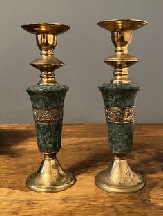 three gold and green vases sitting on top of a wooden table