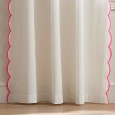 a white curtain with pink scalloped trim