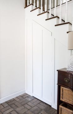 an empty room with white walls and wooden stairs in front of a lamp on a table