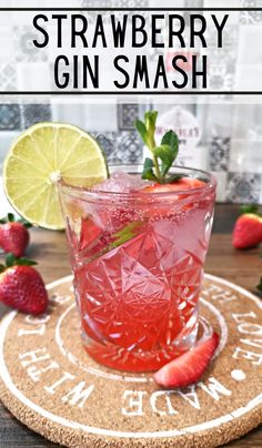 a strawberry gin smash on a cork coaster with strawberries and lime