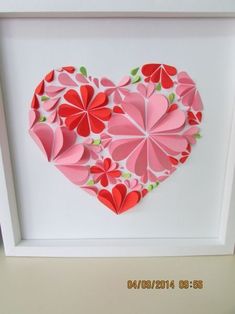 a heart made out of folded paper in a white frame with pink and red flowers