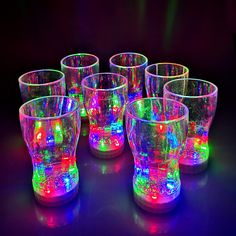 a group of colorful glasses sitting on top of a black table next to each other