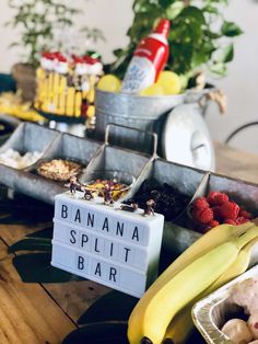 bananas, raspberries, and other fruit are on display in front of a sign that says banana split bar