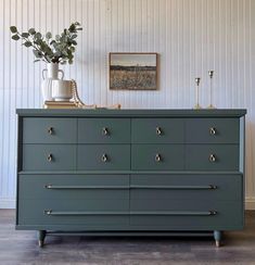 a green dresser with two vases on top