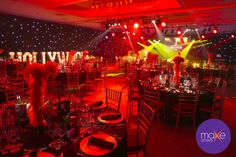 a banquet hall set up for an event with red lighting and black tablecloths