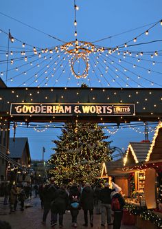 people walking under an archway decorated with lights and christmas decorations at the german market in cologne, germany