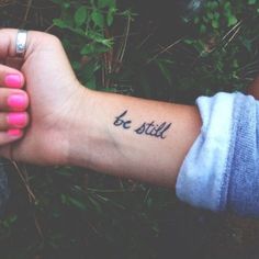 a woman's arm with a tattoo that says be still on the left wrist