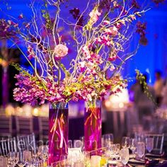 two vases filled with flowers on top of a table covered in plates and silverware