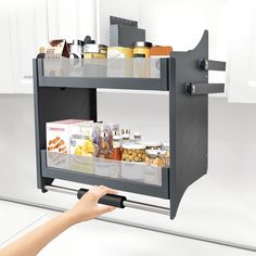 a person is holding a shelf with food in it and pointing to the bottom drawer