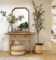 a wooden table sitting next to a mirror on top of a wall near a potted plant