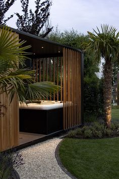 an outdoor hot tub in the middle of a garden with palm trees and gravel path