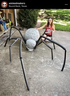 a woman sitting in front of a giant spider sculpture