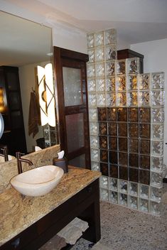 a bathroom with a sink, mirror and glass blocks in the shower stall door area