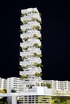 a tall white building with plants growing on it's balconies at night