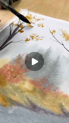 someone is using a brush to paint an autumn scene on a piece of art paper