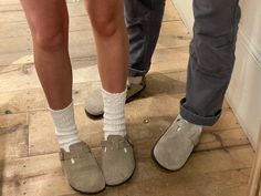 two people standing next to each other wearing slippers and socks with their feet on the ground