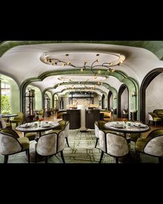 the interior of a restaurant with tables, chairs and chandeliers hanging from the ceiling