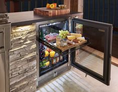 an open refrigerator filled with lots of food next to a counter top oven and sink