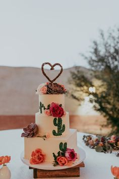 a wedding cake with flowers and a heart on top