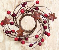 a metal wreath with red berries and star decorations on the top is hanging on a wall