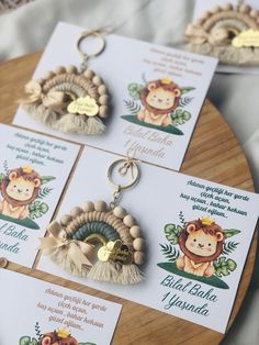 three key chains with animals on them sitting on top of a wooden table next to cards