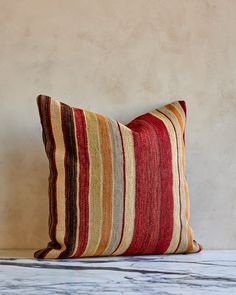 a striped pillow sitting on top of a wooden table next to a white and brown wall