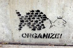 graffiti on the side of a building that says, organize and fish are swimming in it