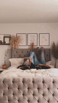 a woman laying on top of a bed in a room with pictures above her head