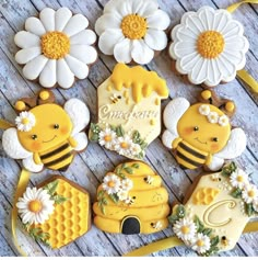 decorated cookies with bees and daisies are arranged on a wooden table next to flowers