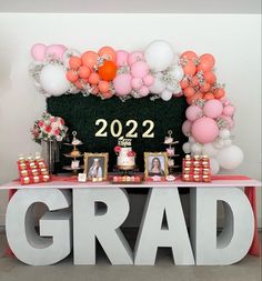 a decorated table with balloons, cake and pictures on it for a graduation party or celebration