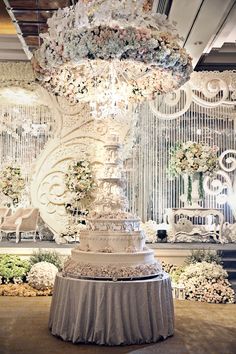 a large white cake sitting on top of a table next to a chandelier