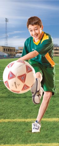 a young boy kicking a soccer ball on a field